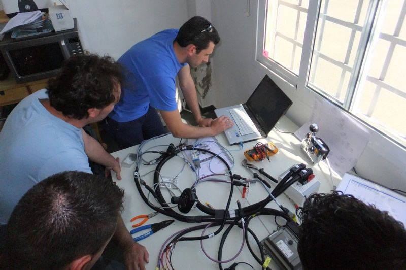 Yacht'UP technicians gathered around a laptop and a wiring harness, working through a control-system diagnosis together.