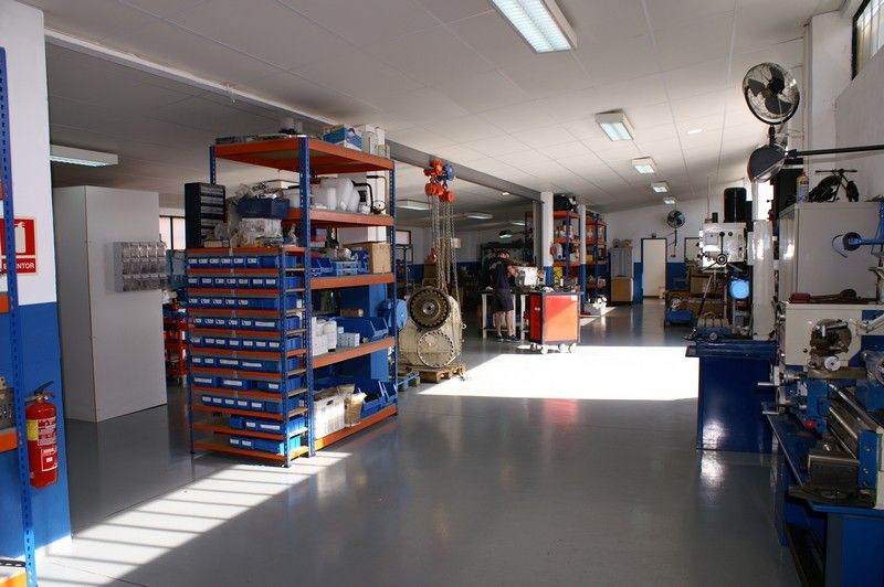 The Yacht'UP workshop floor in Palma de Mallorca, with parts racking, a lifted marine gearbox and machine tools.